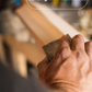 Hand sanding a wooden cricketbat with text 'Sanding the Finished Bat' above - Trogon Cricket