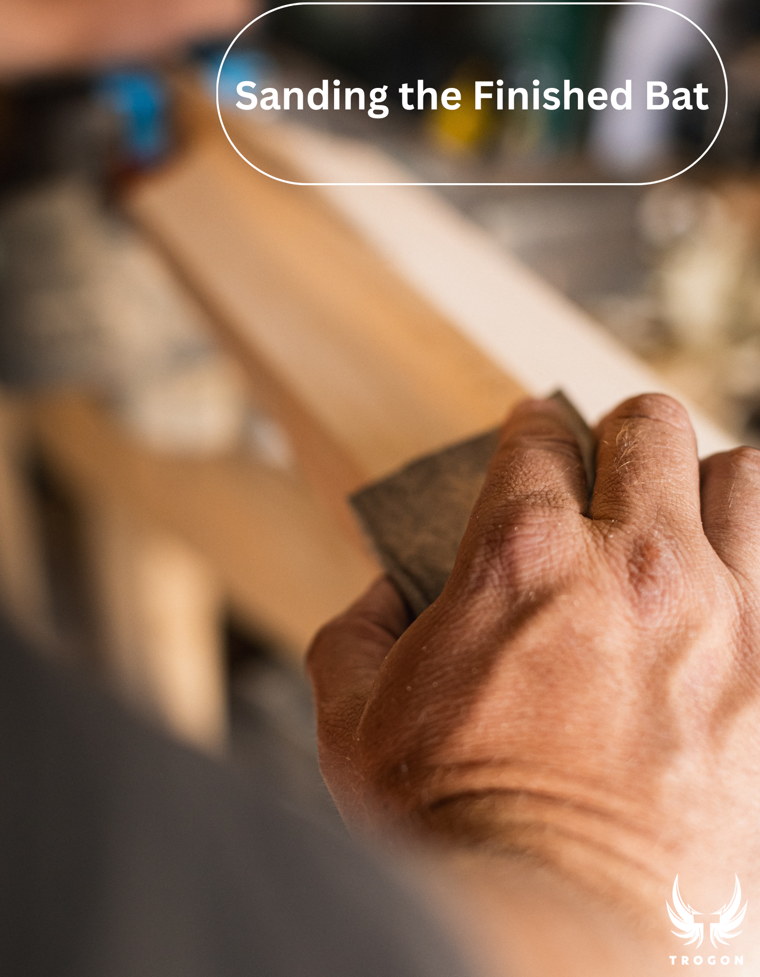Hand sanding a wooden cricketbat with text 'Sanding the Finished Bat' above - Trogon Cricket