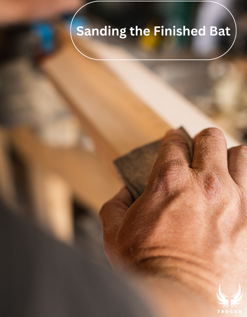 Hand sanding a wooden cricketbat with text 'Sanding the Finished Bat' above - Trogon Cricket