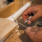 Person stringing a handle on a Trogon Cricket bat with text 'Stringing the Handle' above.