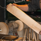 Person polishing a wooden bat with a buffer in a workshop setting - Trogon cricket