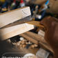 Hand applying glue to a wooden handle with a workshop background