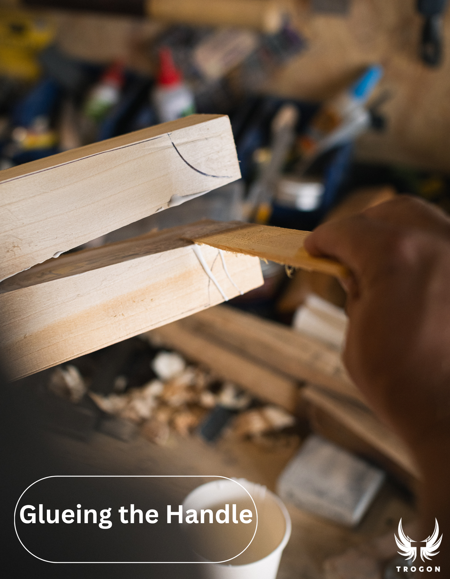 Hand applying glue to a wooden handle with a workshop background