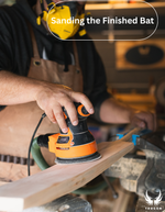 Person sanding a wooden Trogon cricket bat with a sander, wearing a yellow helmet and apron.