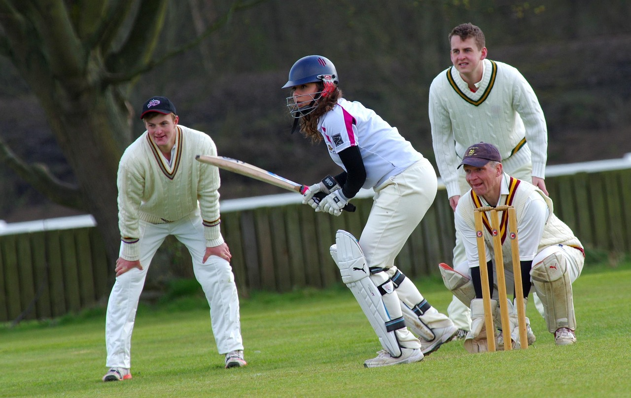 A young female cricketer batting in a mens game looking composed and ready to hit the ball