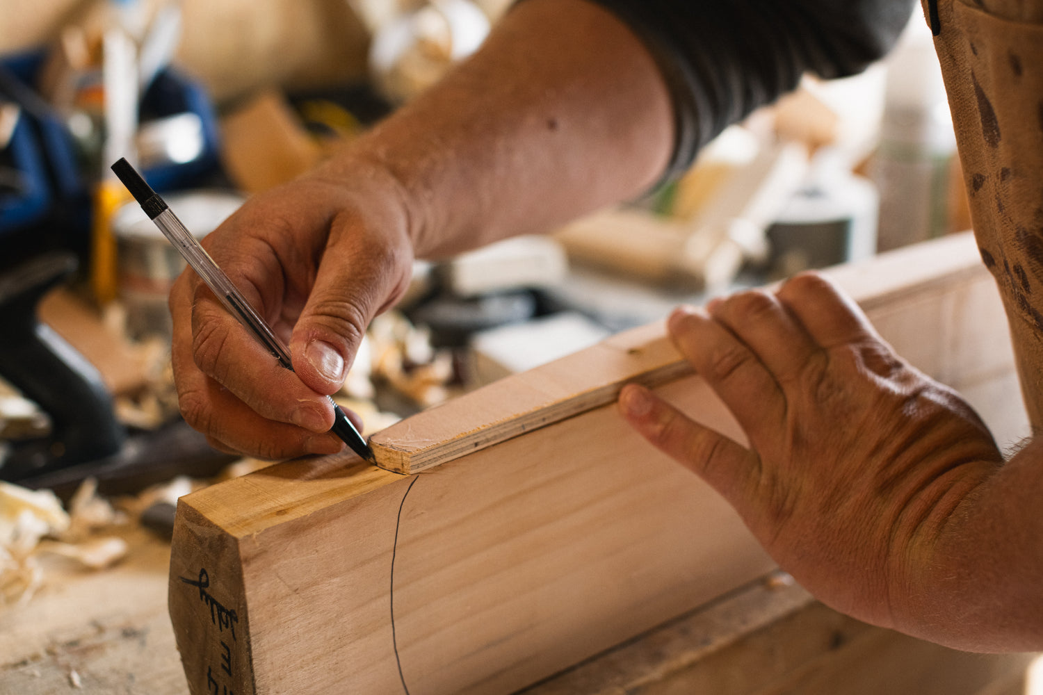 Person working on a wooden project with a pencil in a workshop setting Trogon Cricket