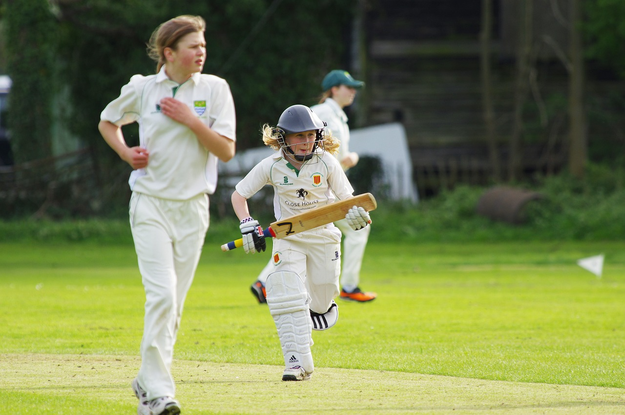 A young girl playing cricket and running between the wickets